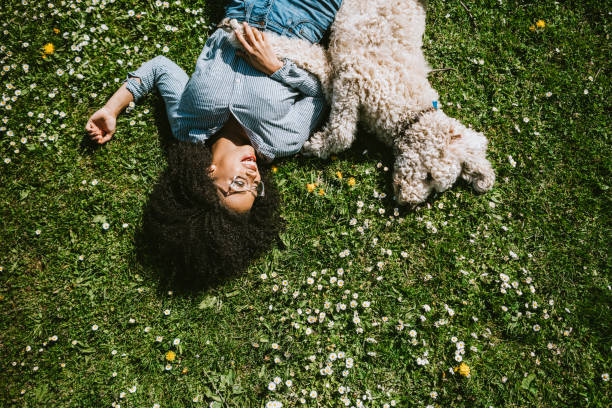 A happy young adult woman enjoys her time at a park with her dog. Credit: RyanJLane